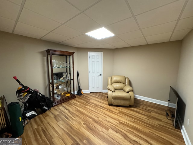 living area with wood-type flooring and a drop ceiling