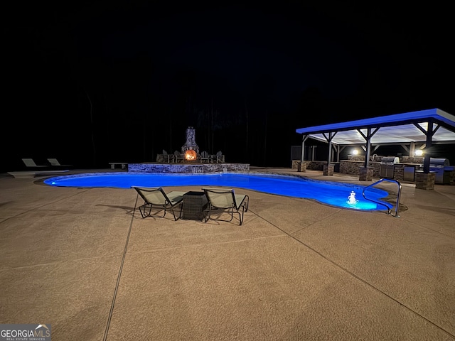 pool at night featuring a patio