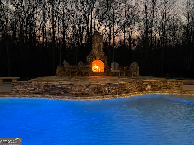 view of pool featuring a patio, pool water feature, and an outdoor stone fireplace