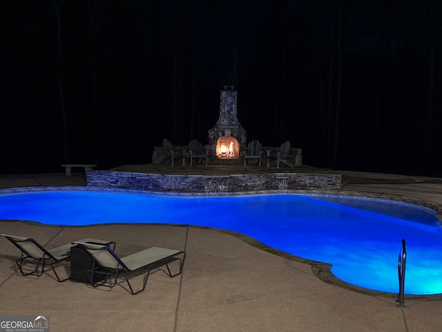 pool at night featuring a patio