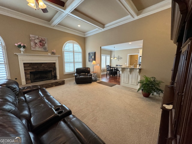 living room featuring beamed ceiling, ceiling fan with notable chandelier, carpet, coffered ceiling, and ornamental molding