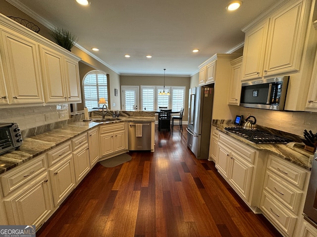 kitchen featuring kitchen peninsula, stainless steel appliances, pendant lighting, dark hardwood / wood-style flooring, and ornamental molding