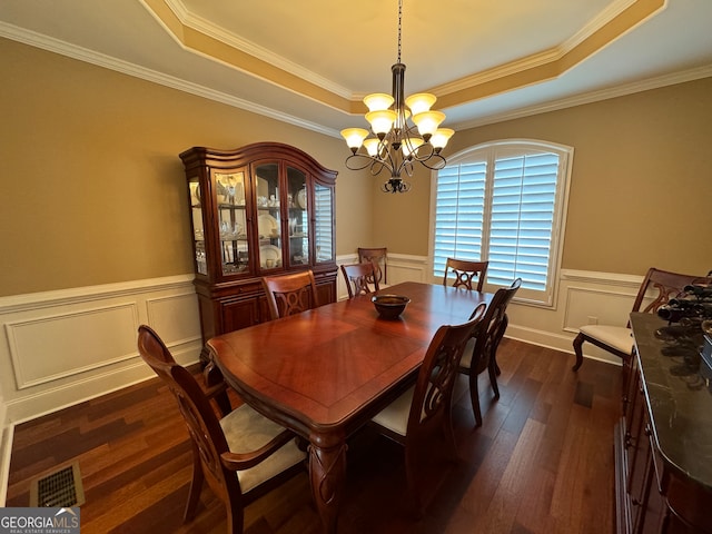 dining room with a notable chandelier, a raised ceiling, and dark wood-type flooring