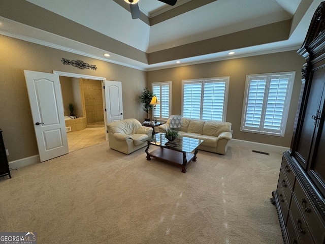 living room with a towering ceiling, ceiling fan, a raised ceiling, crown molding, and carpet floors