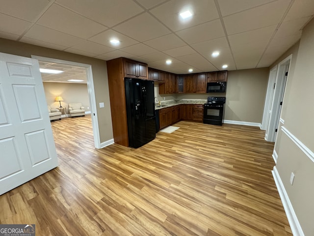 kitchen featuring sink, light hardwood / wood-style flooring, a paneled ceiling, and black appliances