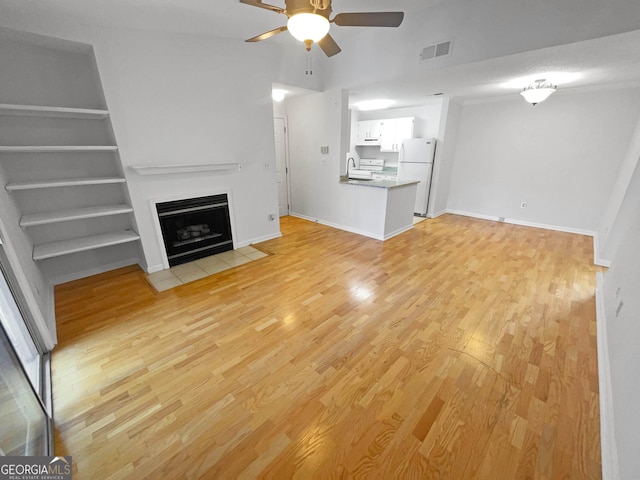 unfurnished living room with ceiling fan, built in features, light hardwood / wood-style floors, and sink