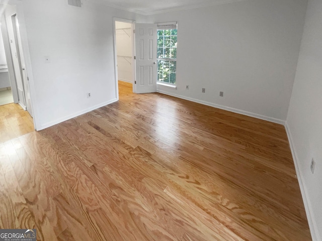 empty room with light wood-type flooring and ornamental molding