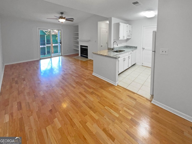 kitchen featuring refrigerator, ceiling fan, sink, built in features, and white cabinets