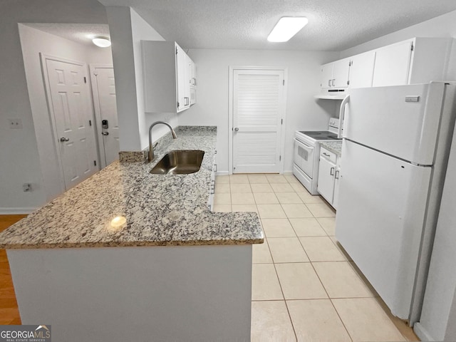 kitchen featuring white appliances, a textured ceiling, sink, light tile patterned floors, and white cabinets