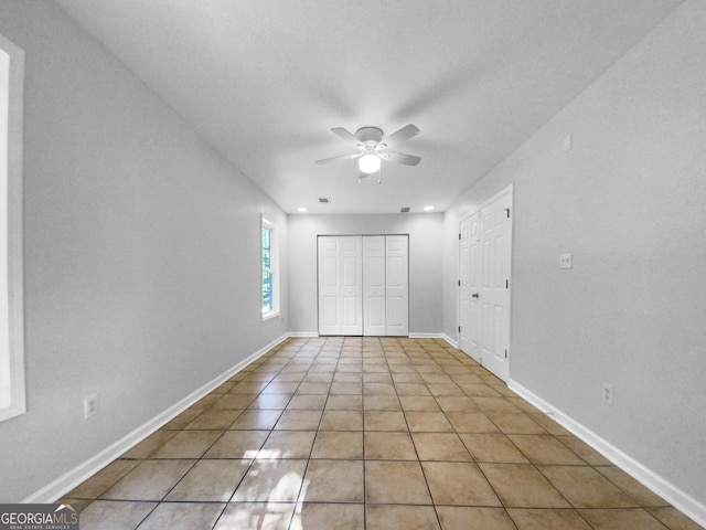 unfurnished bedroom with ceiling fan, light tile patterned flooring, and a closet