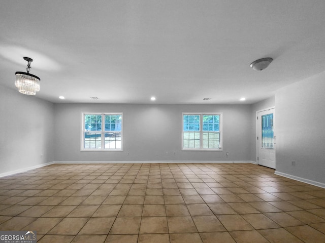 tiled spare room featuring a notable chandelier