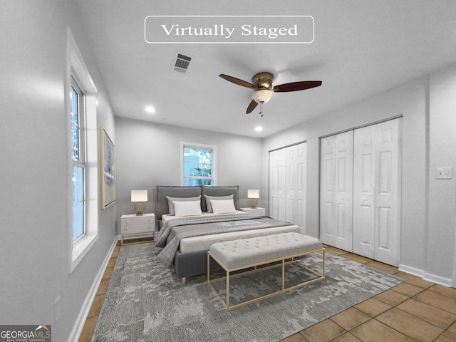 bedroom with two closets, tile patterned floors, and ceiling fan