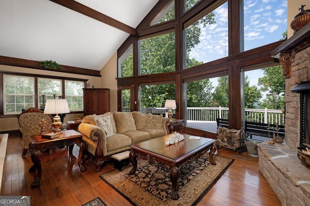 living room with high vaulted ceiling, light hardwood / wood-style flooring, a fireplace, and beam ceiling