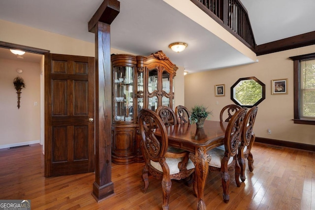 dining area featuring ornate columns and wood-type flooring