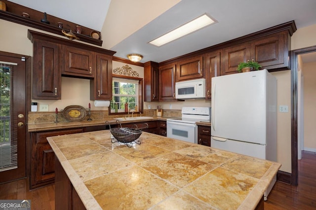 kitchen with dark hardwood / wood-style flooring, sink, vaulted ceiling, white appliances, and a center island