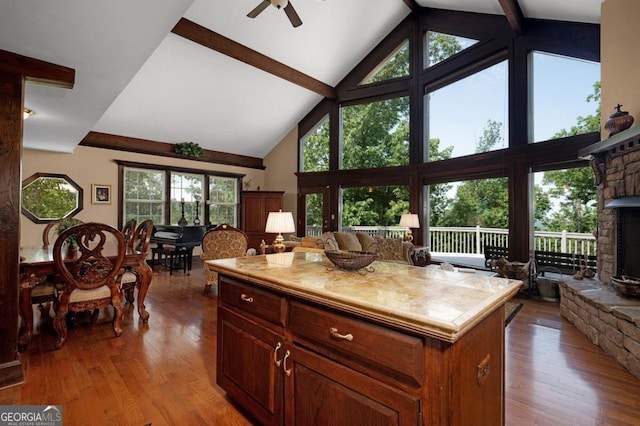 kitchen featuring beam ceiling, high vaulted ceiling, a fireplace, a center island, and light wood-type flooring