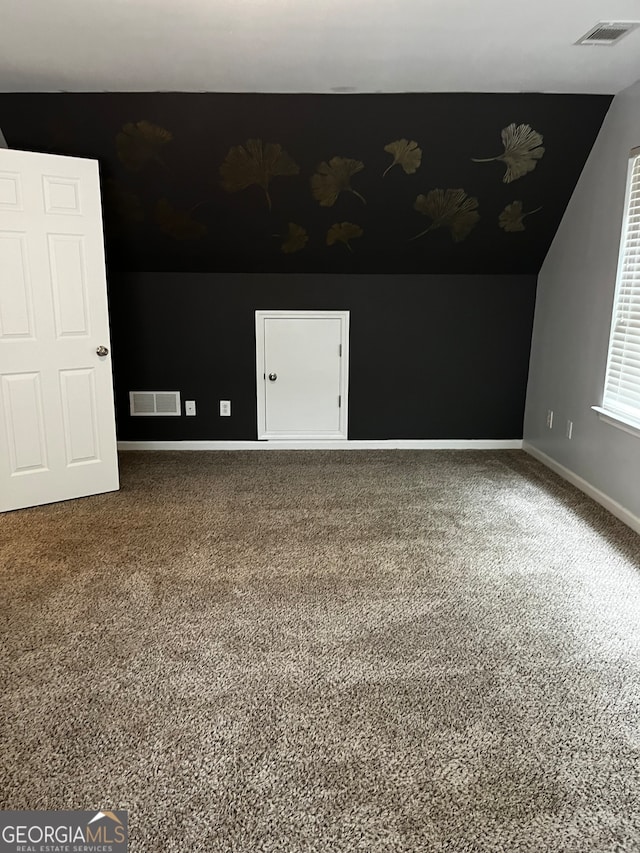 additional living space with dark colored carpet and lofted ceiling