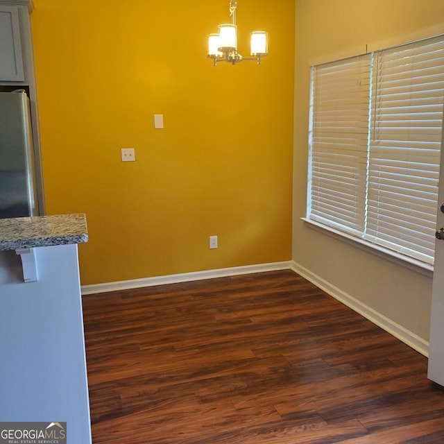 unfurnished dining area featuring dark hardwood / wood-style floors and a notable chandelier