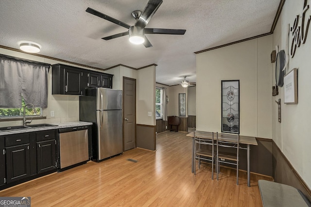 kitchen featuring crown molding, appliances with stainless steel finishes, sink, and light wood-type flooring