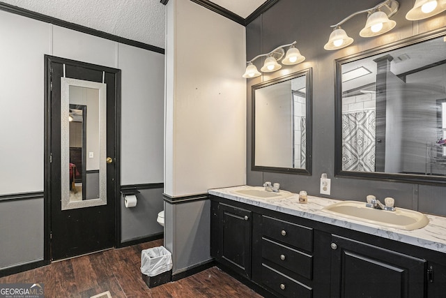 bathroom featuring toilet, wood-type flooring, a textured ceiling, ornamental molding, and vanity