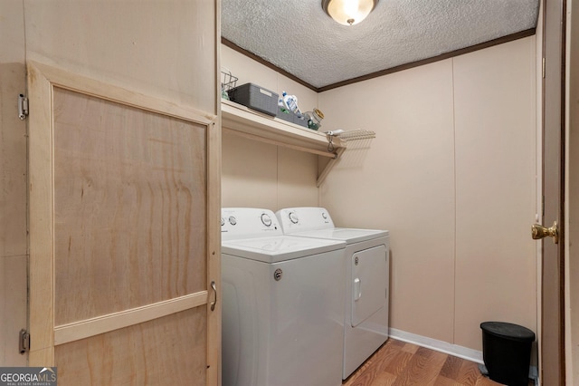 laundry room with hardwood / wood-style flooring, crown molding, a textured ceiling, and washer and clothes dryer