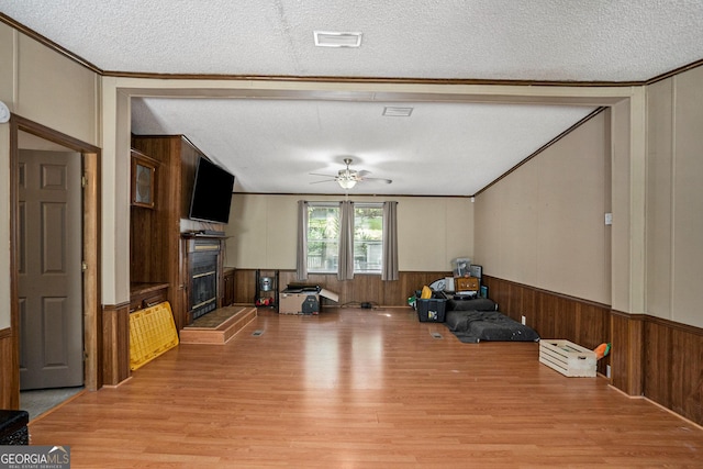 interior space with wooden walls, ornamental molding, light hardwood / wood-style floors, and a textured ceiling