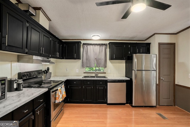 kitchen with stainless steel appliances, sink, a textured ceiling, and light hardwood / wood-style flooring