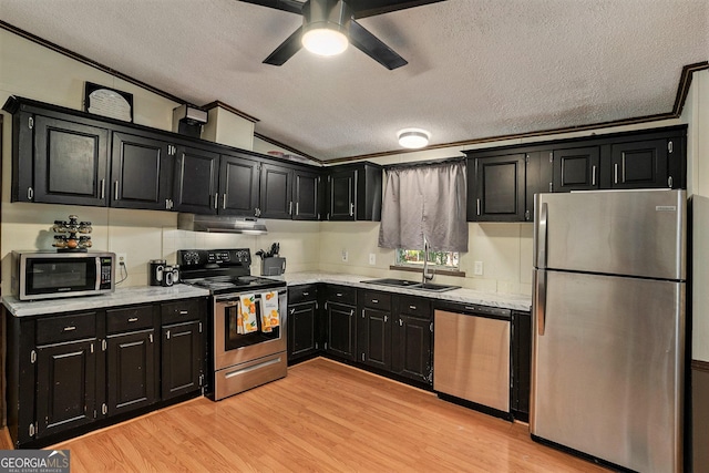 kitchen with vaulted ceiling, sink, stainless steel appliances, crown molding, and light wood-type flooring