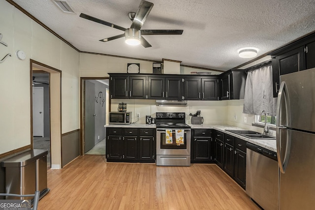 kitchen with vaulted ceiling, appliances with stainless steel finishes, light hardwood / wood-style floors, and sink