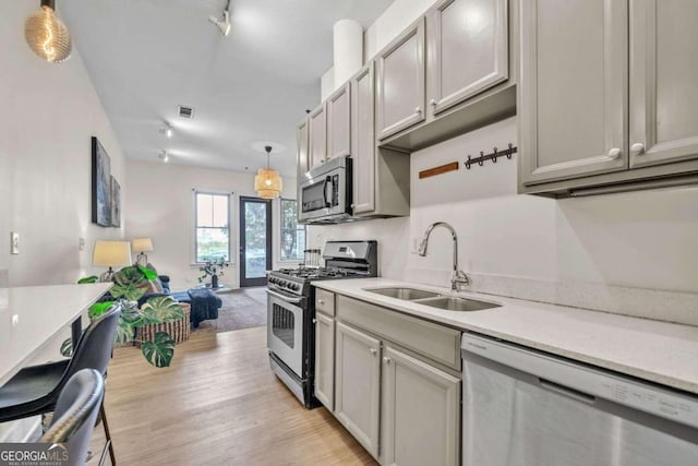 kitchen with decorative light fixtures, sink, gray cabinetry, and stainless steel appliances