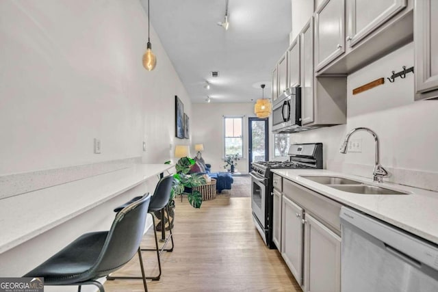 kitchen with appliances with stainless steel finishes, gray cabinetry, hanging light fixtures, and sink