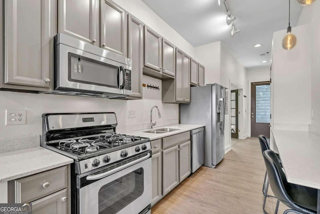 kitchen featuring pendant lighting, sink, light hardwood / wood-style flooring, appliances with stainless steel finishes, and track lighting