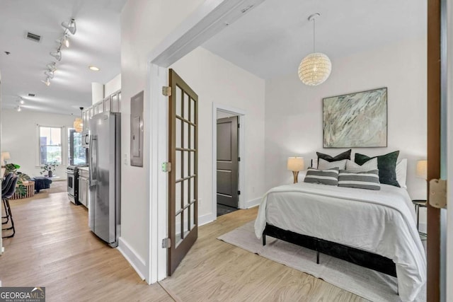 bedroom featuring light wood-type flooring and stainless steel fridge