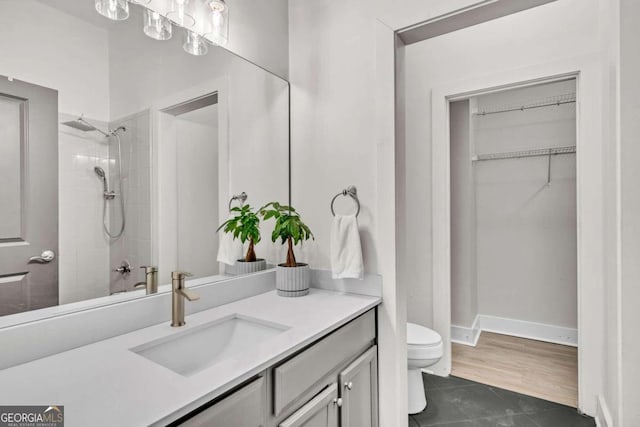 bathroom with tile patterned floors, toilet, vanity, and tiled shower