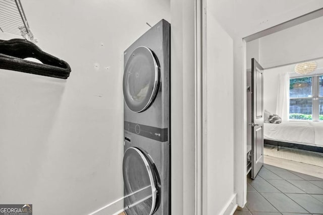 washroom with tile patterned flooring and stacked washer / drying machine