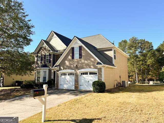 craftsman-style home with a garage, central AC unit, and a lawn