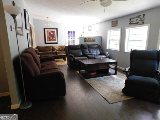 living room featuring dark wood-type flooring, vaulted ceiling, and ceiling fan with notable chandelier