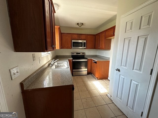 kitchen featuring appliances with stainless steel finishes, light tile patterned floors, and sink