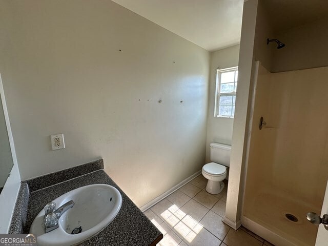 bathroom with tile patterned flooring, vanity, toilet, and walk in shower