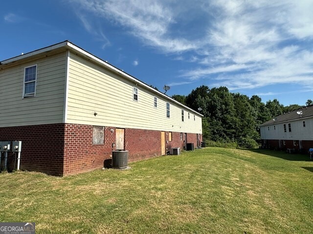 view of property exterior with central AC unit and a yard