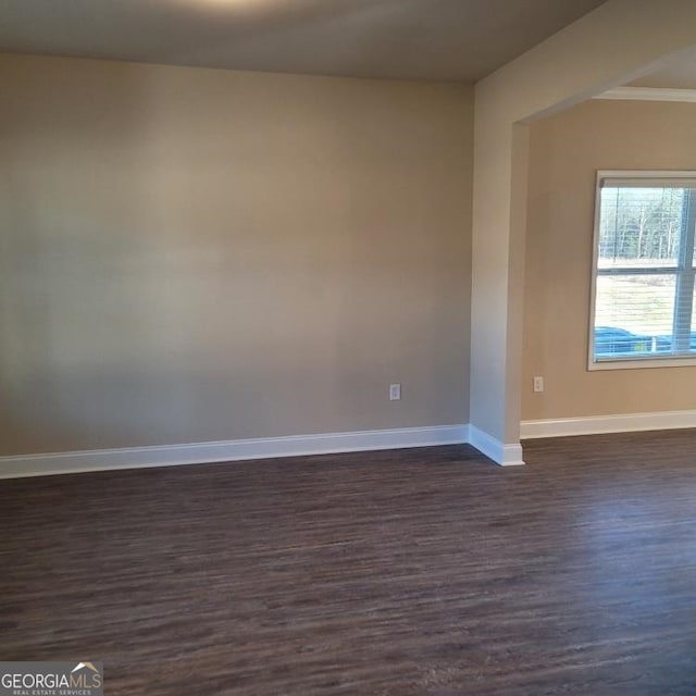 unfurnished room featuring dark wood-type flooring and baseboards