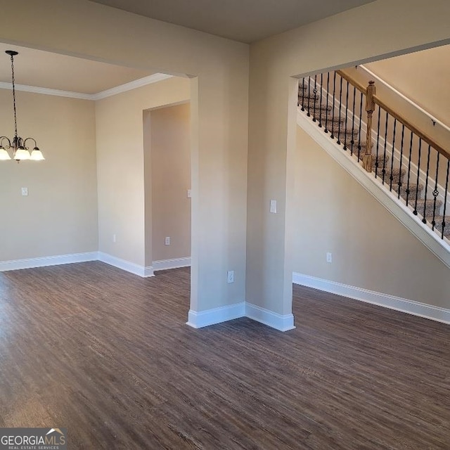 unfurnished living room featuring dark hardwood / wood-style floors, crown molding, and an inviting chandelier