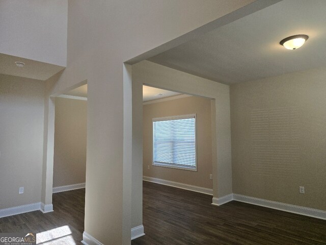 unfurnished room with dark hardwood / wood-style flooring, ornamental molding, and an inviting chandelier