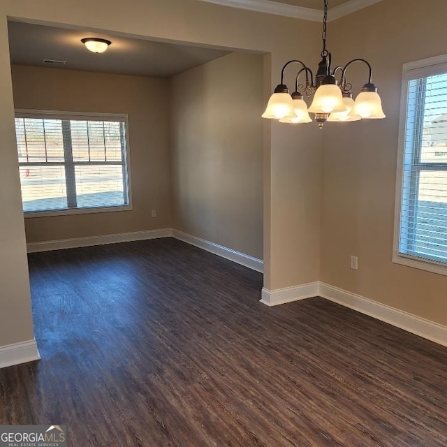 empty room with dark wood-style floors, a notable chandelier, a wealth of natural light, and baseboards