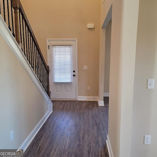 foyer with dark wood-type flooring, stairway, and baseboards