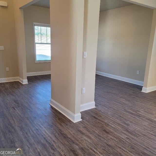 spare room featuring dark wood-type flooring and baseboards