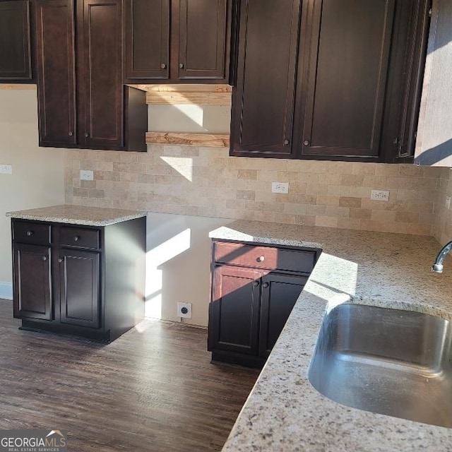 kitchen featuring dark brown cabinets, sink, and light stone counters