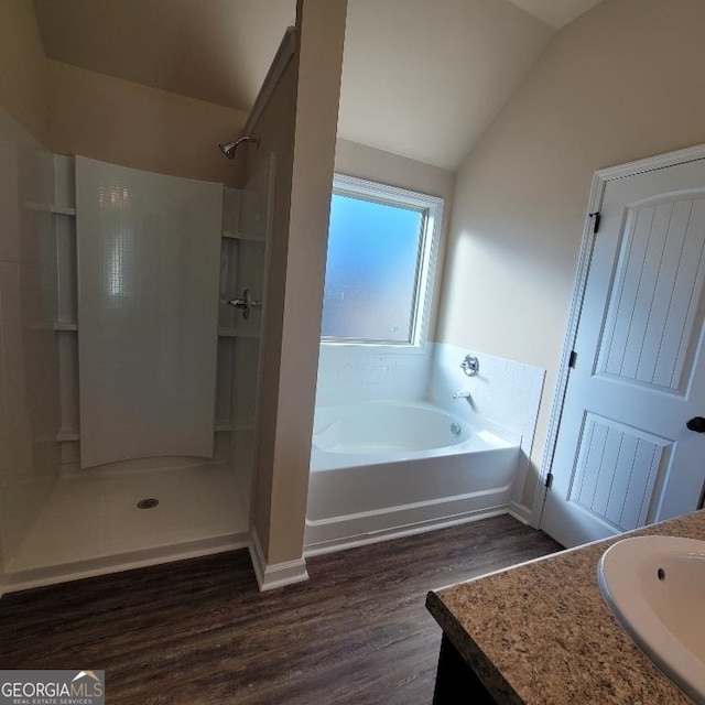 bathroom with independent shower and bath, lofted ceiling, wood-type flooring, and vanity