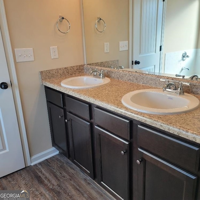 bathroom featuring wood finished floors, a sink, and double vanity