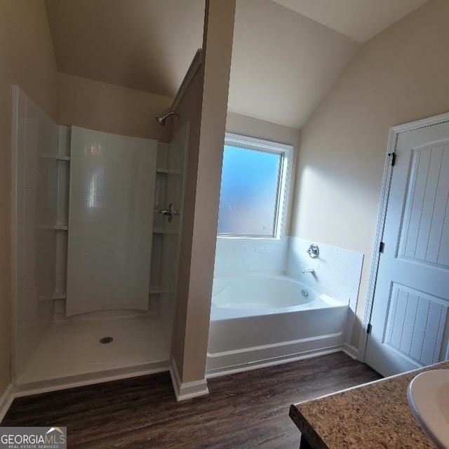 full bath featuring a shower, lofted ceiling, vanity, wood finished floors, and a bath